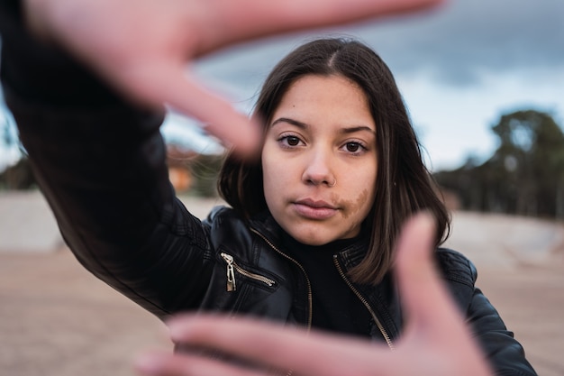 Portret van tienermeisje met een moedervlek op haar gezicht met handen voor haar gezicht.