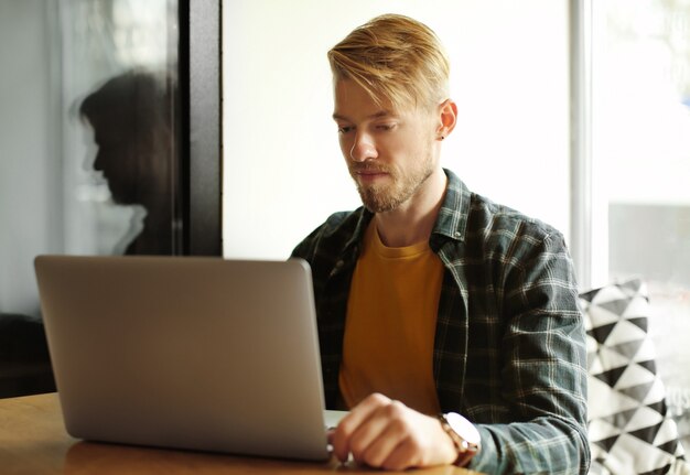 Portret van trendy hipster met laptop in café in