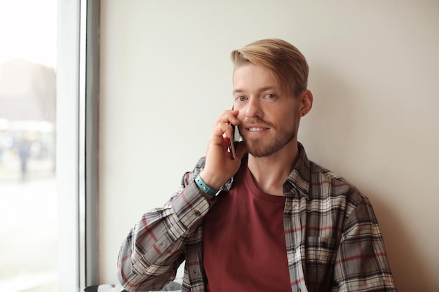 Portret van trendy hipster praten op mobiele telefoon in café