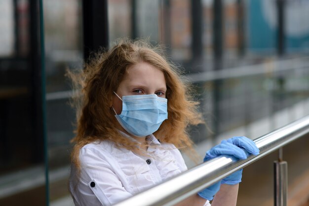 Foto portret van triest kaukasisch kind in gezichtsmasker op gesloten speelplaats buiten.