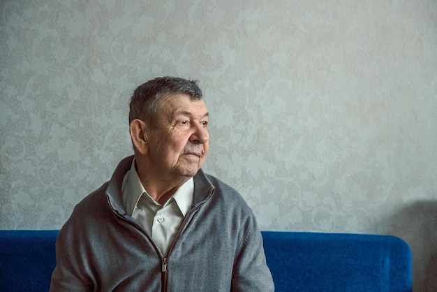 Portret van trieste oudere man op grijze achtergrond doordachte blik van oude senior die alleen thuis zit
