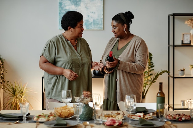 Portret van twee afro-amerikaanse vrouwen die een tafel serveren voor een familiediner thuis