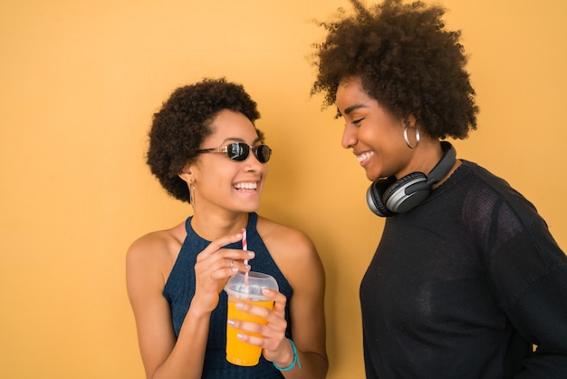 Portret van twee Afro-vrienden die samen plezier hebben en genieten van een goede tijd terwijl ze vers vruchtensap drinken. Vriendschap en levensstijl concept.