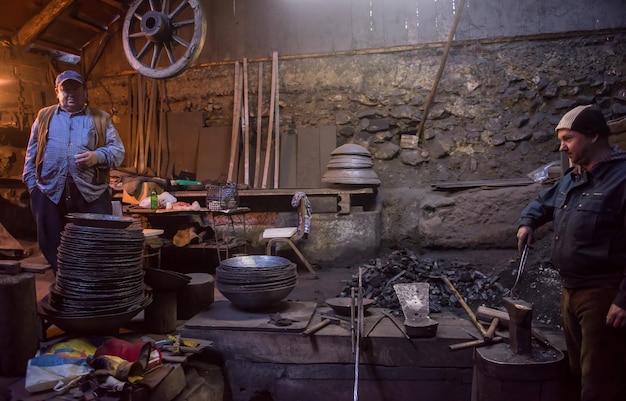 portret van twee generaties traditionele zelfverzekerde smidsarbeiders in werkplaats