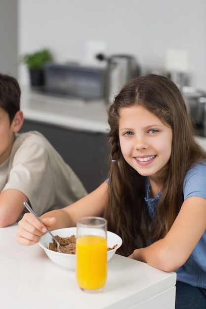 Portret van twee glimlachende broers en zussen die van ontbijt genieten