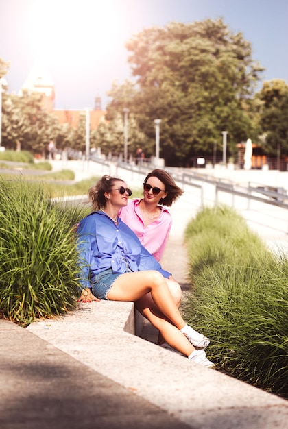 Portret van twee jonge, mooie glimlachende hipster-vrouwen in trendy zomerkleurkleren, zorgeloze vrouwen die zich voordeed op rivierachtergrond Positieve modellen die plezier hebben met knuffelen