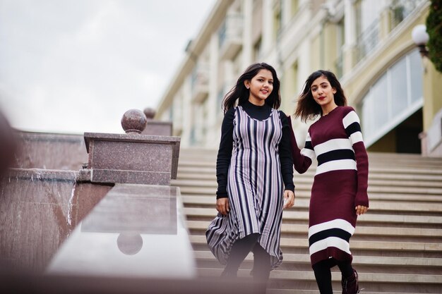 Portret van twee jonge mooie Indiase of Zuid-Aziatische tienermeisjes in jurk geposeerd op trappen op city