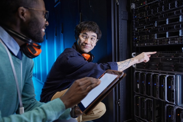 Foto portret van twee jonge technici die een servernetwerk opzetten terwijl ze in het datacenter werken, kopieer ruimte