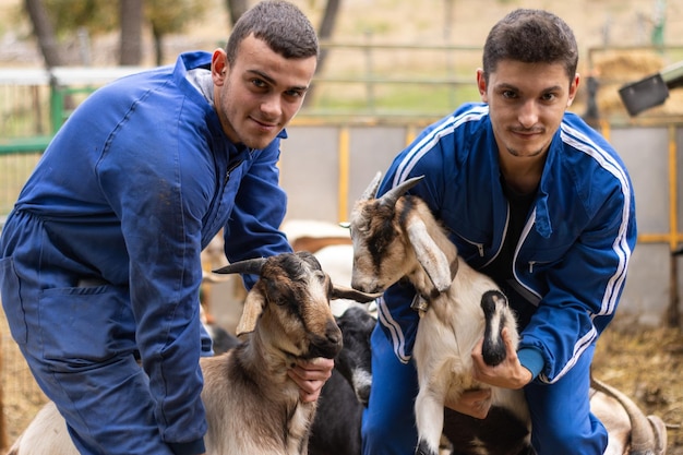 Portret van twee jonge veehouders met hun geiten op hun erf. concept van jonge mensen die in de veehouderij en landbouw werken