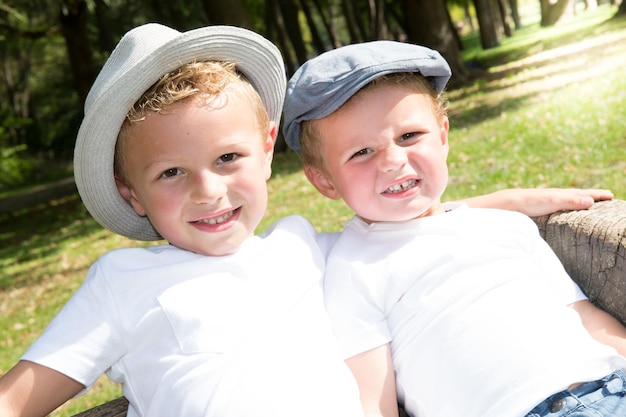 Portret van twee kind broer broer of zus jongen met een blij gezicht met een pet in de zomertuin