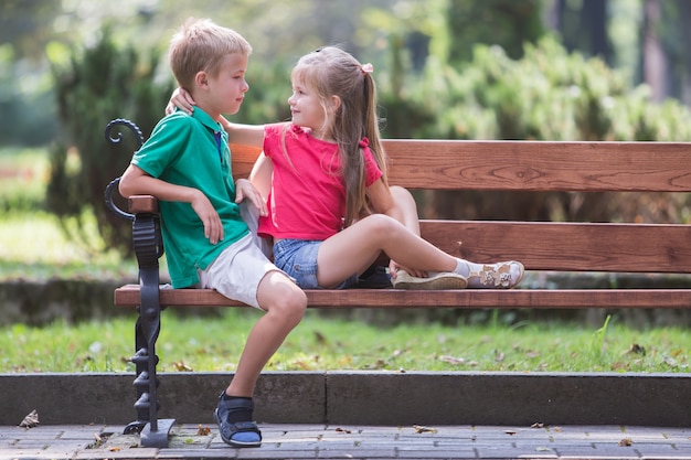 Portret van twee kinderenjongen en meisje die prettijd op een bankje in de zomerpark hebben.