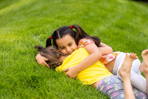 Portret van twee kleine meisjeszusters die vechten op de achtertuin van het huis. Vrienden meisjes plezier. Lifestyle openhartig familiemoment van broers en zussen die ruzie maken om samen te spelen.