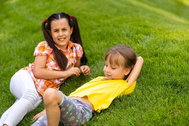 Portret van twee kleine meisjeszusters die vechten op de achtertuin van het huis. Vrienden meisjes plezier. Lifestyle openhartig familiemoment van broers en zussen die ruzie maken om samen te spelen.