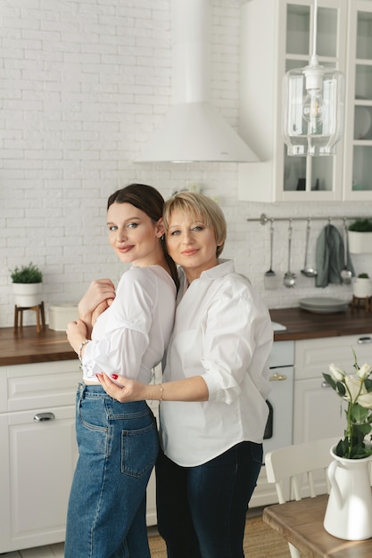 Portret van twee mooie aantrekkelijke mooie tedere vrolijke vrouwen moeder volwassen dochter tijd samen doorbrengen in de keuken