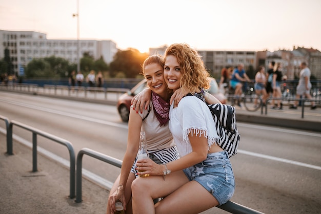 Portret van twee mooie jonge vrouwelijke vrienden die op het festival van de de zomermuziek koesteren.