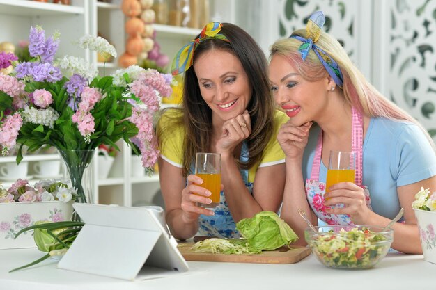 Portret van twee mooie jonge vrouwen die samen koken in de keuken