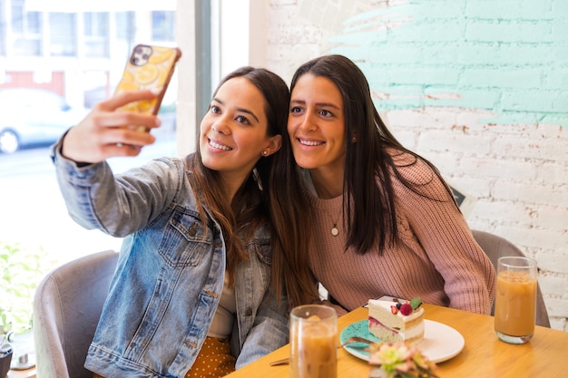 Foto portret van twee mooie vriendinnen selfie foto nemen in een coffeeshop