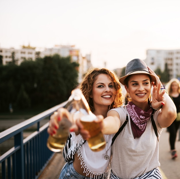 Foto portret van twee partijmeisjes die en in de zomer drinken toejuichen.