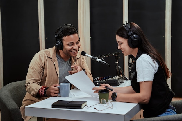 Portret van twee radiopresentatoren, man en vrouw die met elkaar praten terwijl ze een script aan het lezen zijn