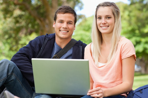 Portret van twee studenten die terwijl het zitten met laptop lachen