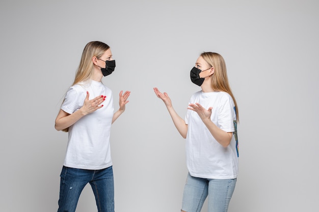 Portret van twee tienermeisjes met lang blond haar met zwarte medische maskers