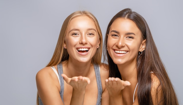 Portret van twee vrolijke jonge vrouwen die samen staan en knuffelen.