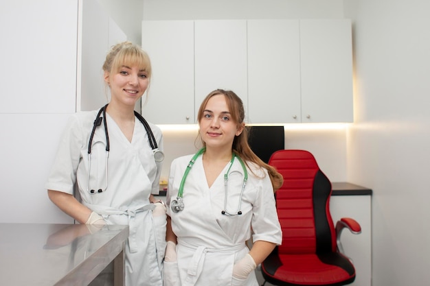 Portret van twee vrouwelijke artsen in medische jassen in de kliniek tegen de werkplek