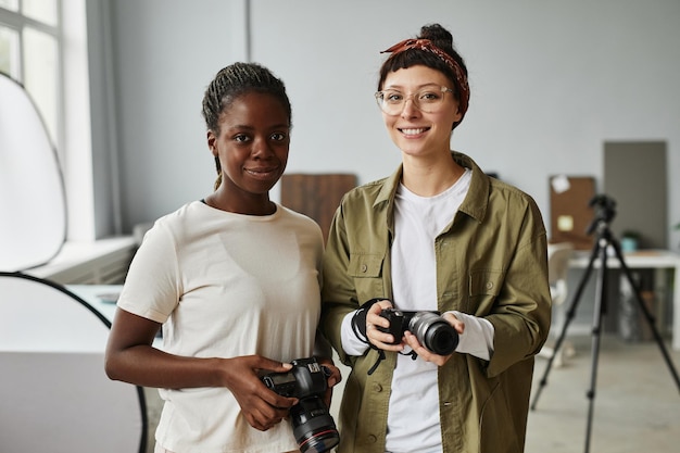 Portret van twee vrouwelijke fotografen die naar de camera glimlachen terwijl ze in de kopieerruimte van de fotostudio staan