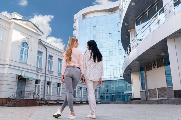 Portret van twee vrouwen die met haar rug naar de camera staan tegen de achtergrond van een hoog glazen gebouw