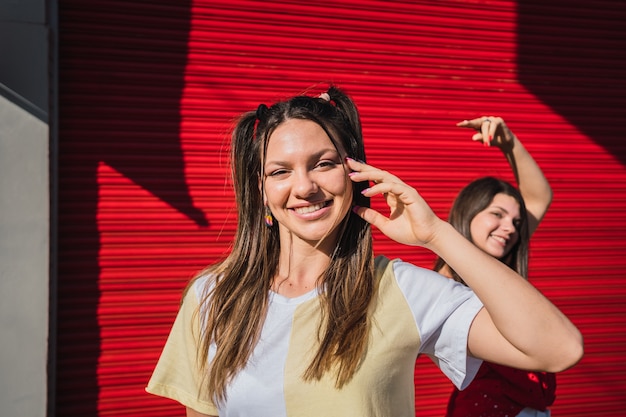 Portret van twee vrouwen die zich op de achtergrond van een rode muur vermaken