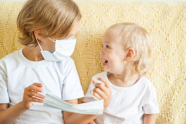 Portret van twee zussen die medische beschermende maskers opzetten, de oudere zus helpt de jongere