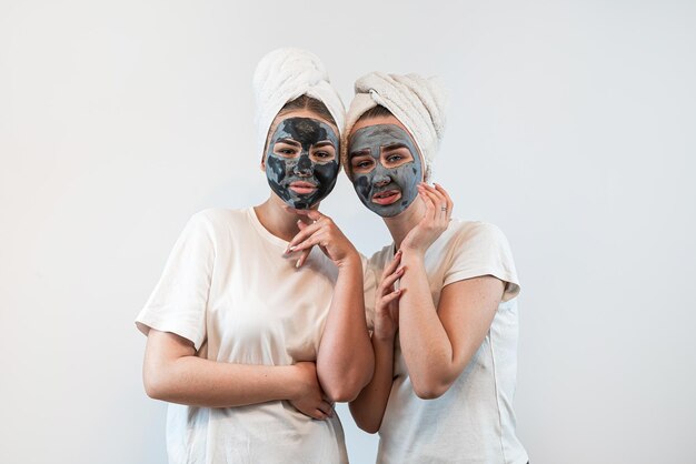 Portret van twee zussen of vriendin maken huid gezichtsmasker geïsoleerd op wit