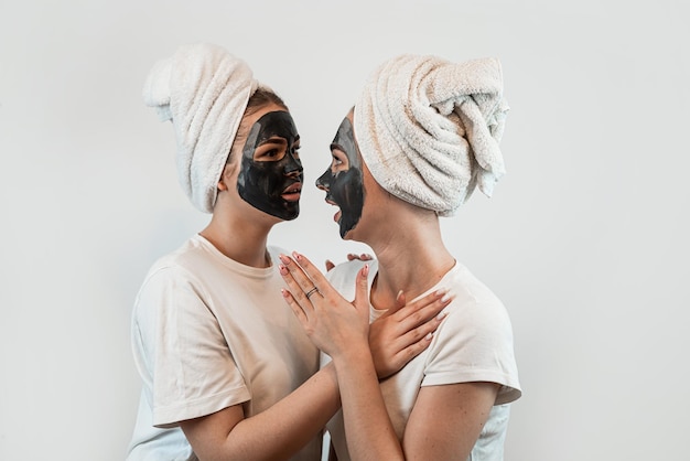 Portret van twee zussen of vriendin maken huid gezichtsmasker geïsoleerd op wit