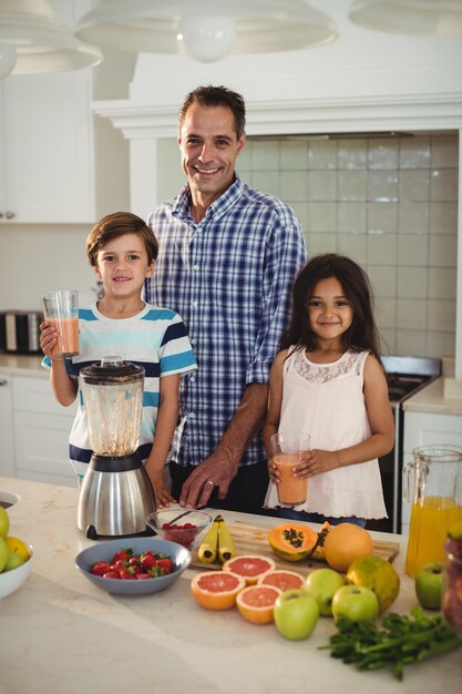 Portret van vader en kinderen houden glas smoothie