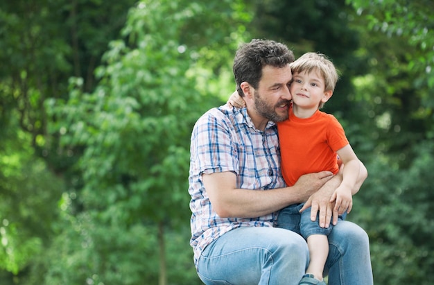 Portret van vader met zoon die tegen bomen zit