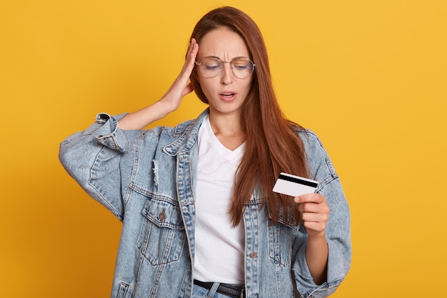 Portret van verbaasd jonge vrouw gekleed denim jasje en wit overhemd, mond open houden, hand op hoofd zetten