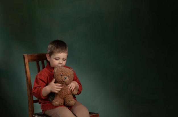 Portret van verdrietig jongetje met teddybeer op groene achtergrond