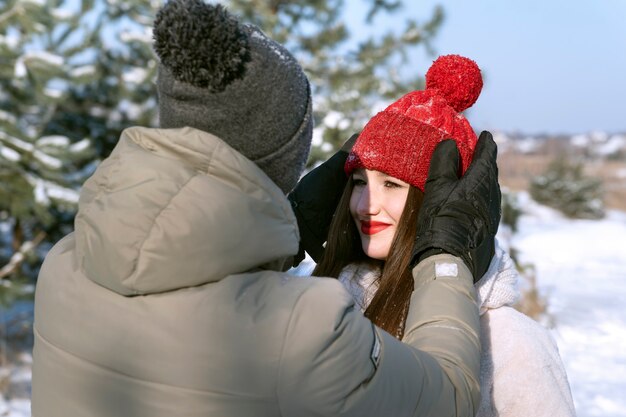 Portret van verliefde paar in de winter buiten. Guy rechtzetten zijn geliefde meisjeshoed.