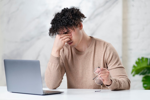 Portret van vermoeide kerel jonge gefrustreerde overwerkte man gevoel pijn vermoeide ogen bril in de hand te houden