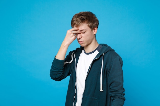 Portret van vermoeide uitgeputte jonge man in casual kleding met gesloten ogen hand op gezicht geïsoleerd.