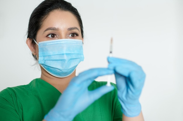 Portret van verpleegster met medisch masker en beschermende handschoenen met spuit met vaccin tegen coronavirus