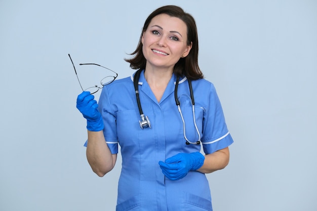 Portret van verpleegster vrouw in blauw uniform, stethoscoop en handschoenen, bril te houden