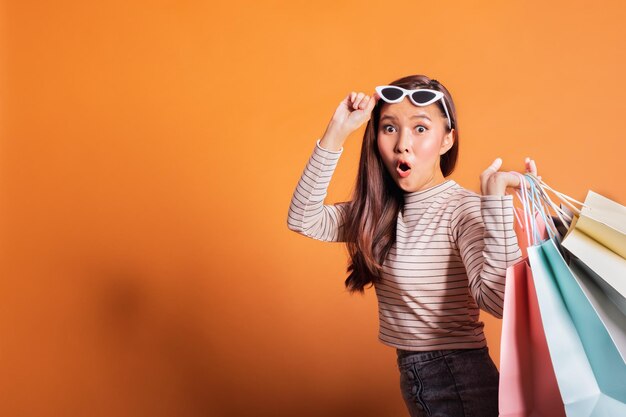 Foto portret van verrast vrouw met boodschappenzakken tegen oranje achtergrond