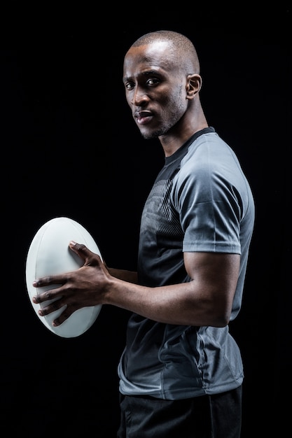 Portret van vertrouwen atleet permanent met rugbybal