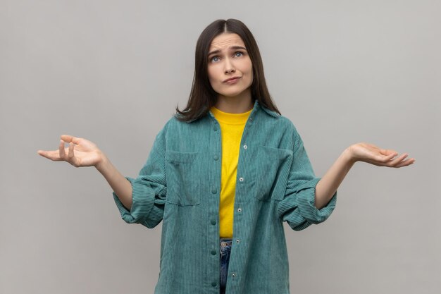 Portret van verwarde mooie jonge vrouw staande opgeheven armen verward en denkend