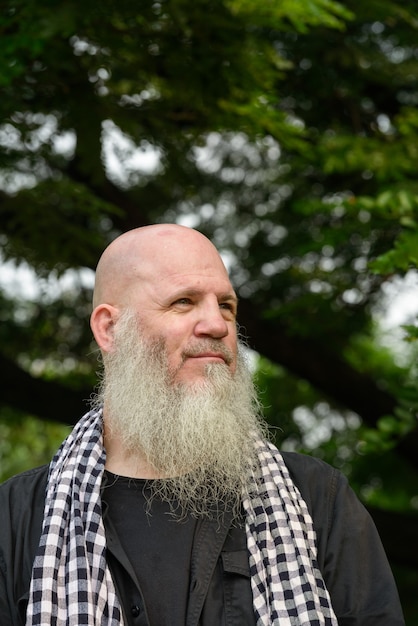 Portret van volwassen kale hipster man met lange baard in het park buiten