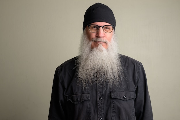 Portret van volwassen kale man met lange grijze baard tegen witte muur