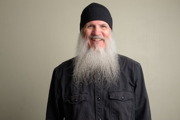 Portret van volwassen kale man met lange grijze baard tegen witte muur