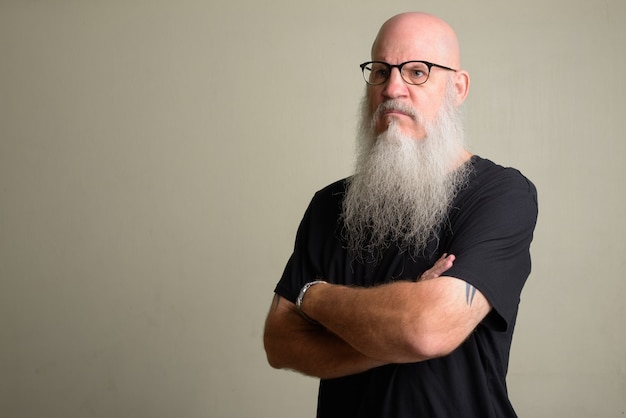 Portret van volwassen kale man met lange grijze baard tegen witte muur