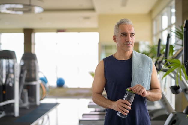 Portret van volwassen knappe Perzische man met grijs haar die traint in de sportschool